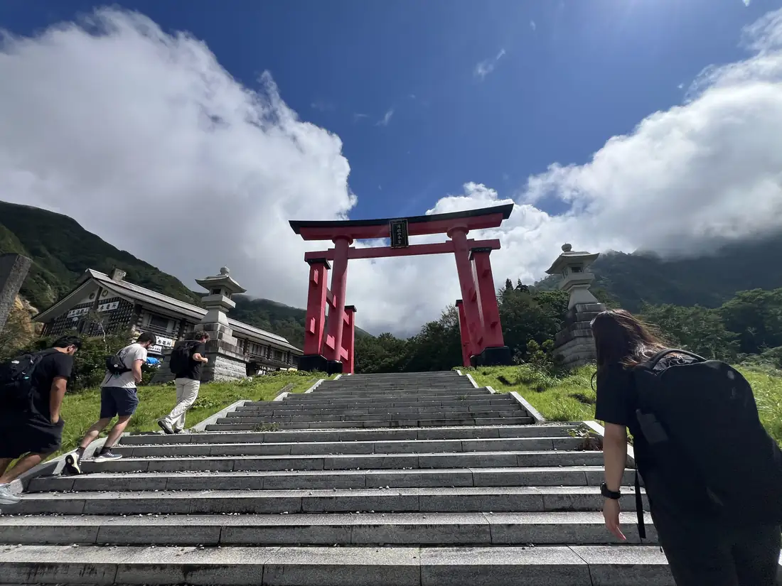 Stone steps lead up to the great vermilion torii gate at Mount Yudono
