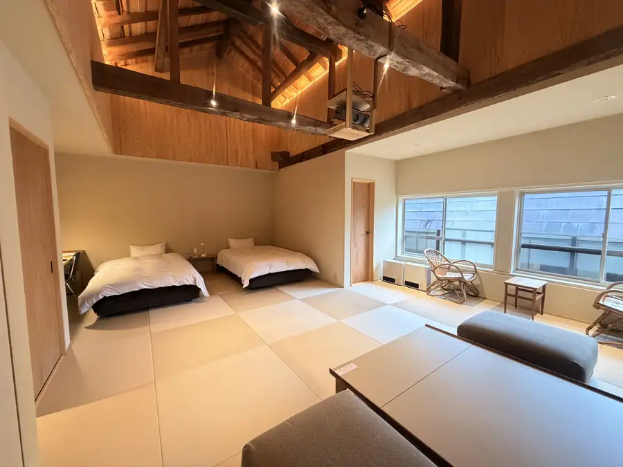 A room at the inn with two beds, tatami flooring and exposed wooden beams
